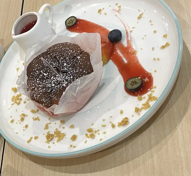 Dessert in baking paper with berry sauce and blueberries