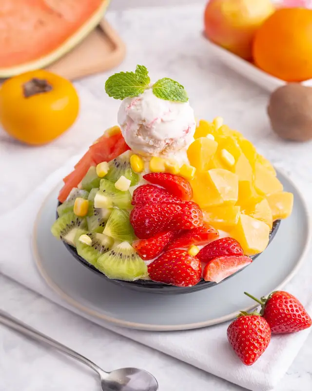 Bingsu topped with strawberries, mango, kiwi, corn and a scoop of ice cream