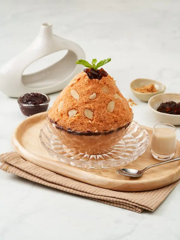 Thai tea bingsu with almond slices and a mint leaf