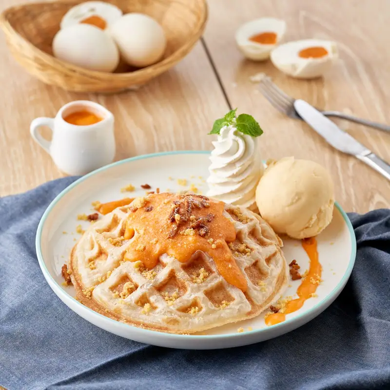Waffle with an orange sauce, whipped cream and a scoop of ice cream